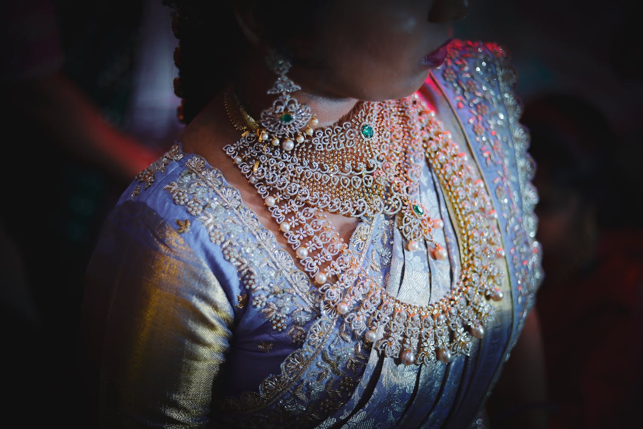 Close-up of a bride wearing intricate jewelry and traditional Indian clothing.